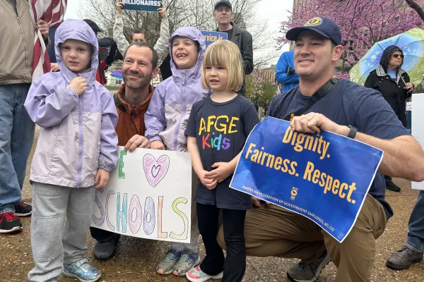 Members at an AFGE rally with their kids holding a sign saying "Dignity, Fairness, Respect." 