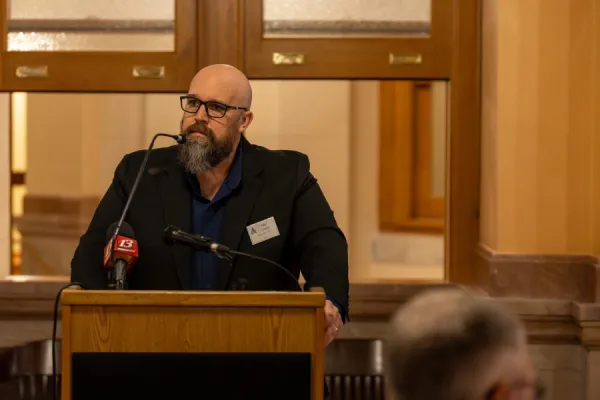 Executive Secretary Treasurer Jake Lowen at podium in Kansas Statehouse